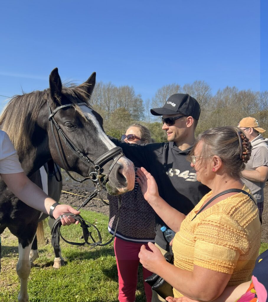 kolm inimest silitamas mustavalge kirjut hobust.