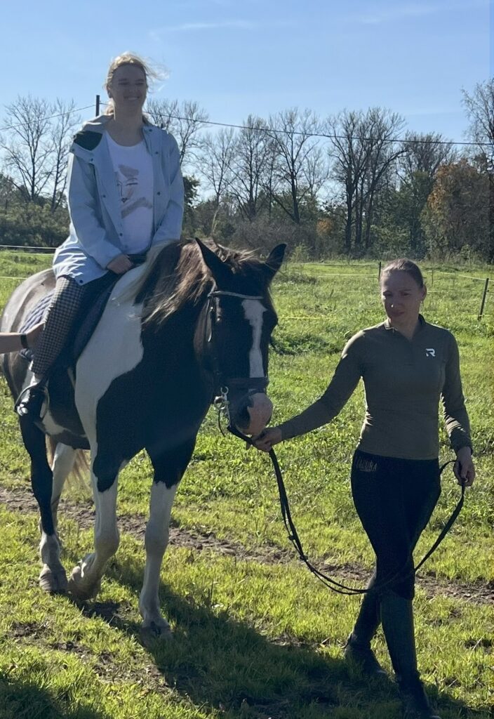 Üks inimene on jõudnud hobuse selga ja teine juhatab hobust rakmetest.