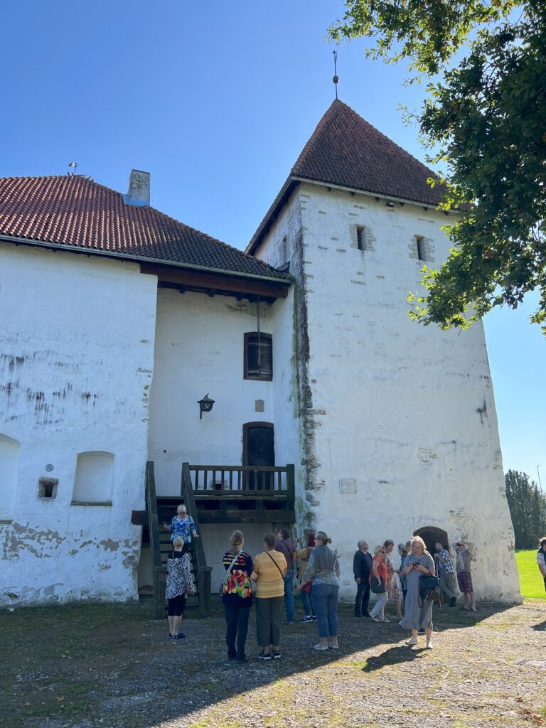 Grupp inimesi ajaloolise vana kivist lossi ees. Lossi teisele korrusele viib õues puidust trepp.