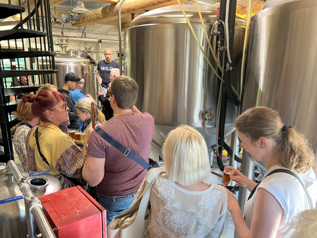 Grupp inimesi ilmselt õlletehases, sest ruumis on palju suuri terasest vaate, mis torude ja voolikutega ühendatud. Tumedas teesärgis, Wild kirjaga mees seisab poodiumil ja räägib inimestele, kes teda kuulavad.