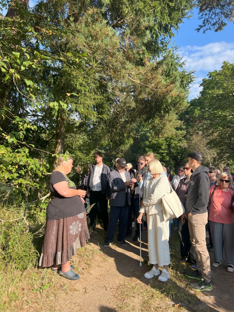 grupp inimesi kesk loodust heledais rõivais giidi kuulamas.